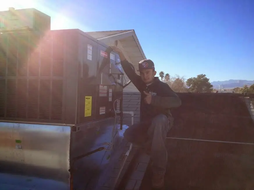 HVAC technician performing Air Duct Cleaning on a rooftop unit in Richmond